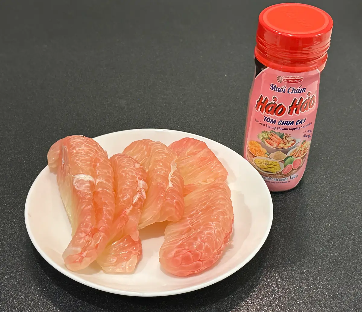 皮をむいたザボンの果肉と、ベトナムで人気の塩唐辛子「ハオハオ(Hảo Hảo)ムオイチャム トムチュアカイ(Muối Chấm Tôm Chua Cay、エビ・辛味風味のディッピングソルト)」の実物写真