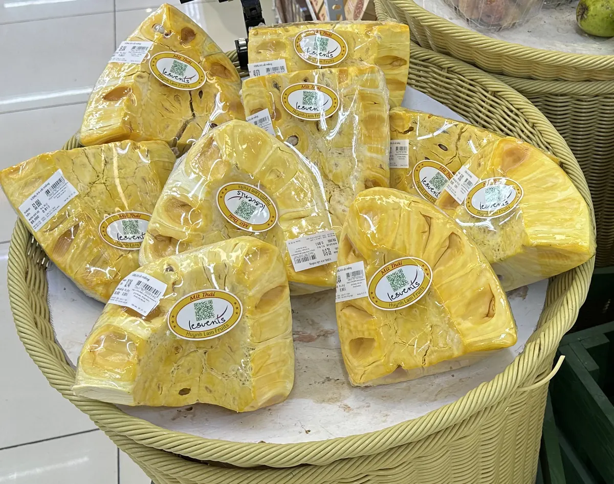 果物店の店頭で見かけたジャックフルーツの陳列。「Mít Thái」のシールが貼られたむき身のブロックが籠に積まれ、それぞれに個別の値札(重量・価格)が付いている実写真
