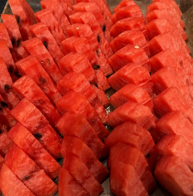 一口大に切り分けられた赤いスイカの果肉が、金属製のトレーに並んでいる様子