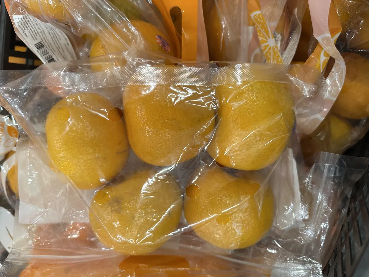 透明なパックに5個入ったオレンジが買い物かごの中に置かれている