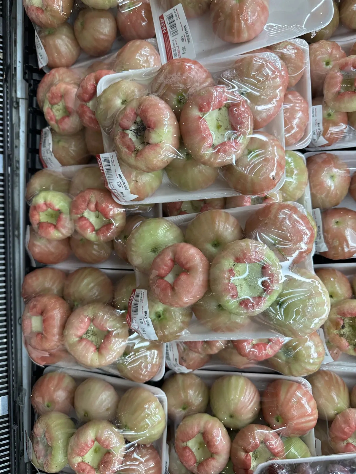 スーパーの陳列棚に並ぶ、ピンク種のレンブ(パッケージ表示:MAN DA DUONG)のパック詰め写真。値札には単価8,500ドン(100gあたり)、内容量860g・914gなどとともに合計金額が表示されている