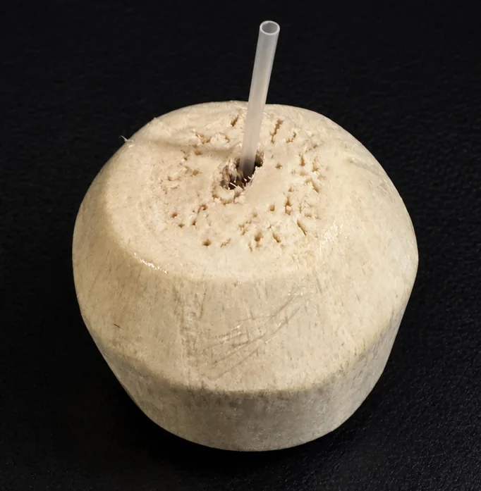 外皮を削ってストローを挿した飲用のココナッツ