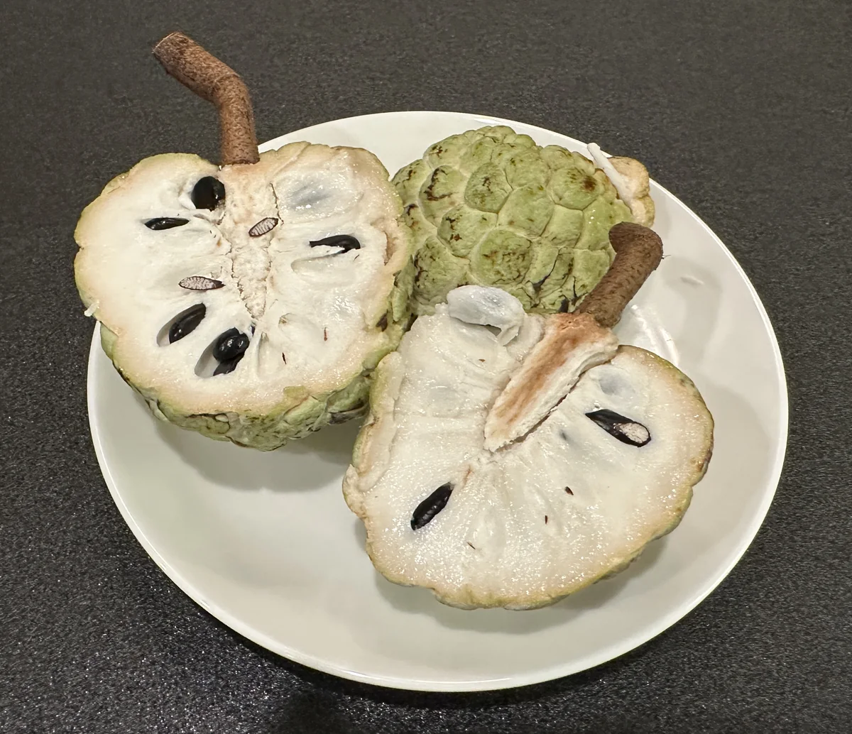 半分に切ったカスタードアップルの白い果肉と黒い種