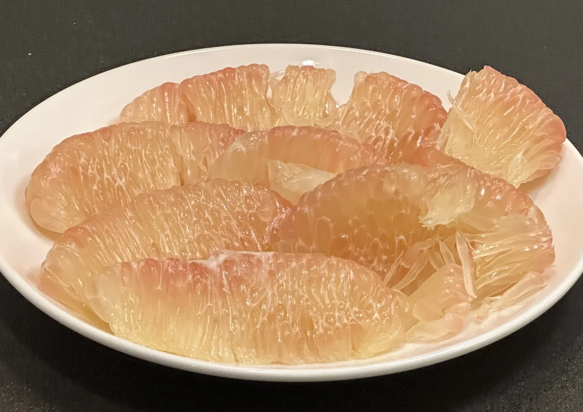 皿に盛った皮をむいたピンク色のザボンの果肉